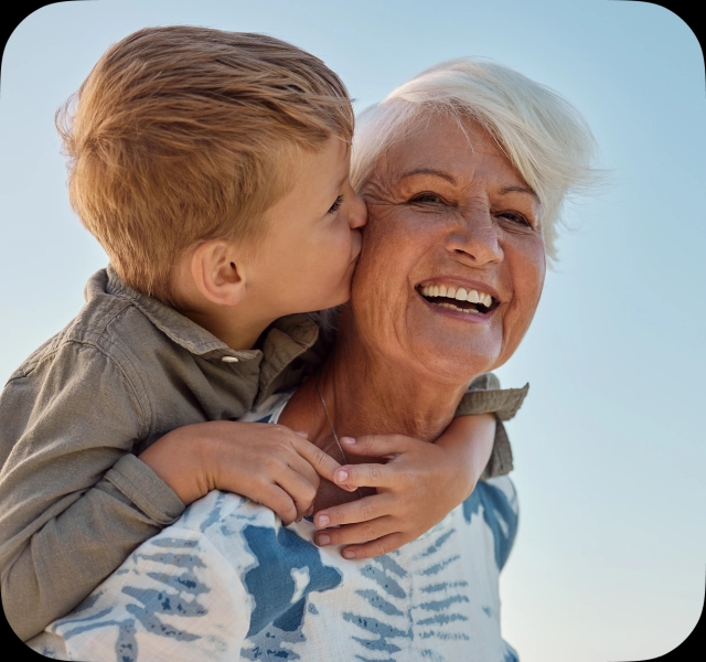 A young child kisses his grandmother on the cheek.