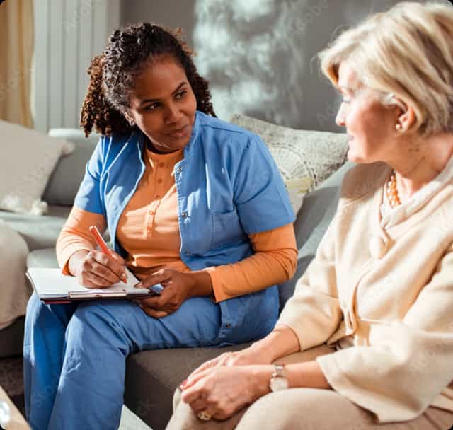 A nurse and an elderly patient laugh together.