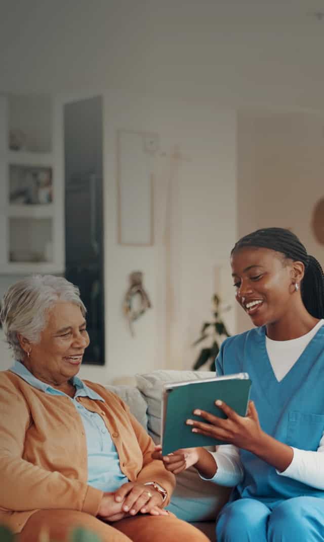 A female nurse helpfully addresses an elderly patient.