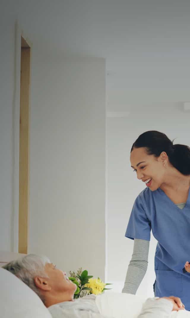 A female nurse helpfully addresses an elderly patient.